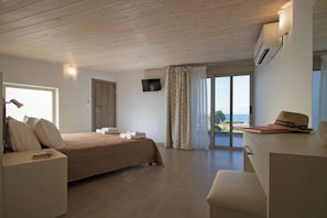 A bedroom with a bed, bedside table, desk, and a view of the sea through a large window. - Enali Villas-Mirti Villa (Kissamos)