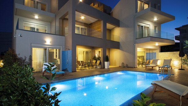 Un immeuble moderne à plusieurs étages, doté d’une piscine, d’un espace extérieur aménagé et d’un intérieur bien éclairé.