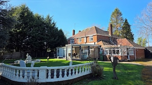 A two-story house with a conservatory, a fenced garden, and a clear blue sky. - Redlands (Bickenhill)