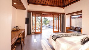 A bedroom with a wooden ceiling, a bed, a desk, and a sliding glass door leading to a balcony. - Taru Sebatu Villa  (Sebatu)