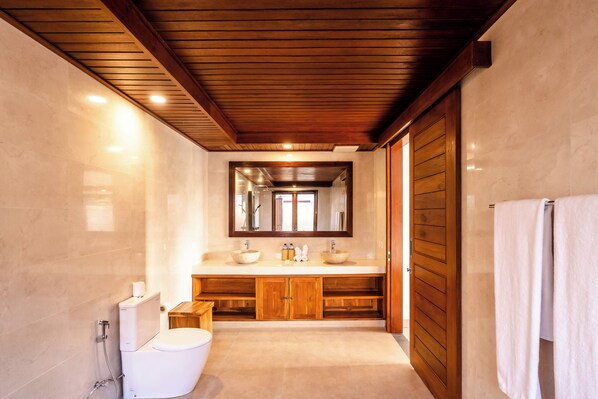 A bathroom with a wooden ceiling, a large mirror, a sink with two basins, and a toilet. - Taru Sebatu Villa (Sebatu)