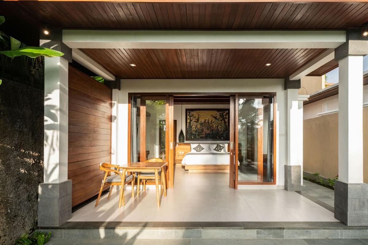Un dormitorio moderno con una cama grande, un comedor con mesa y sillas, y vistas al exterior.