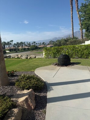 A landscaped area with a stone fountain, palm trees, and a view of distant mountains. - 3-bedroom estate in beautiful La Quinta with AC (La Quinta)