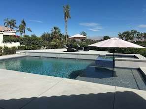 A swimming pool with a tiled edge, lounge chairs, and umbrellas. - 3-bedroom estate in beautiful La Quinta with AC (La Quinta)