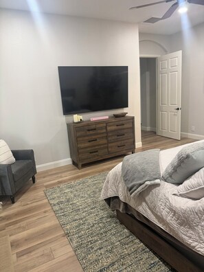 A bedroom with a bed, a dresser, a television, and a door leading to another room. - 3-bedroom estate in beautiful La Quinta with AC (La Quinta)