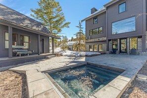 Ein modernes Haus mit Swimmingpool, Steinmauern und einer Bank.
