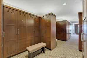Un couloir avec des casiers en bois, un banc et une moquette à motifs.