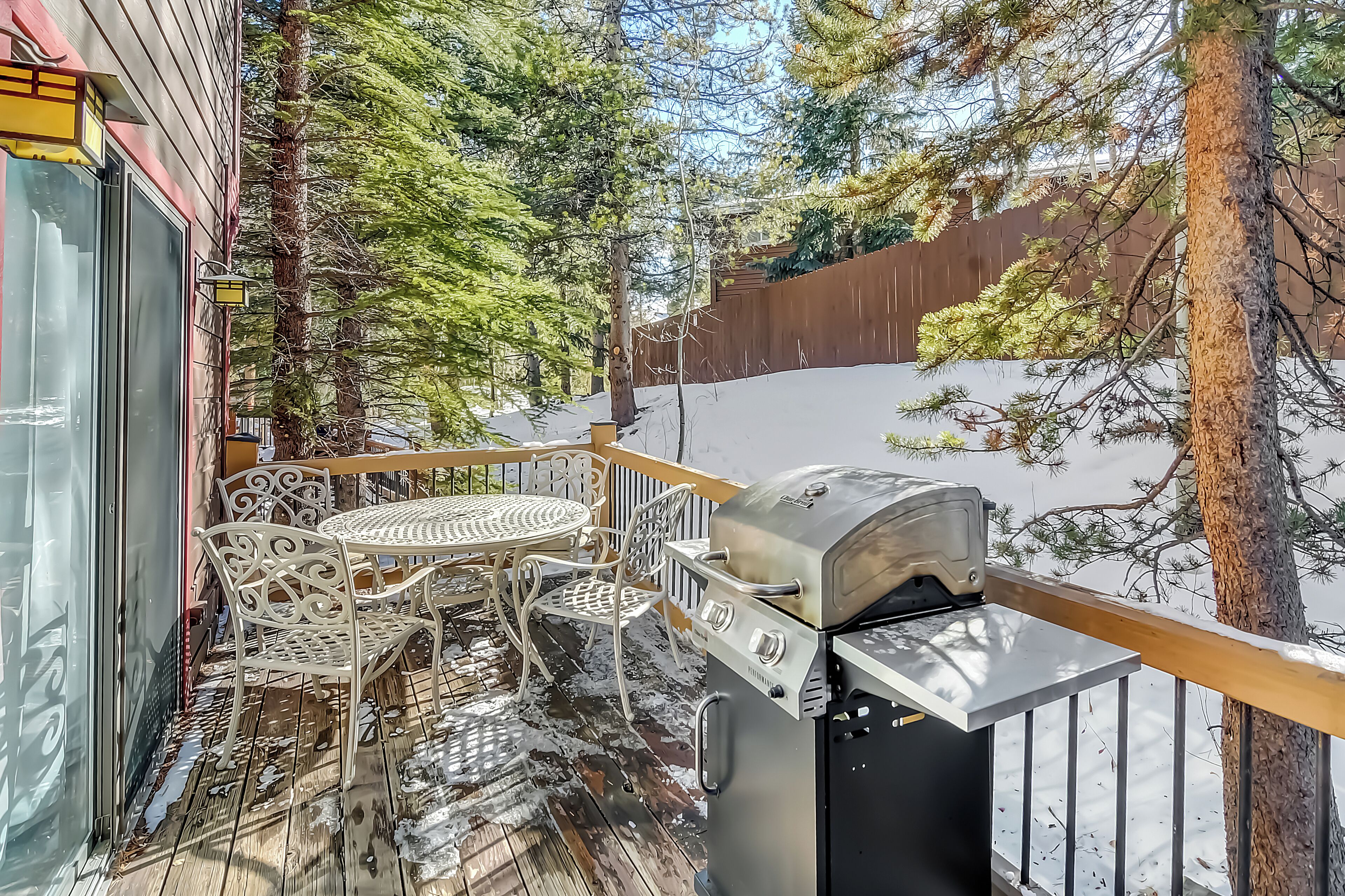 A covered outdoor area with a grill, metal chairs, and a table.