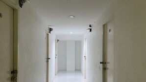 A long, narrow hallway with white walls and doors, leading to a bright room at the end. - ON'S Place (Pattaya)