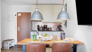 A dining area with a wooden table, two brown leather chairs, and two pendant lights. - Apartment in the 'Krabbenkiste' Hotel with Sea View, Shared Garden, and Wi-Fi (Wunstorf)