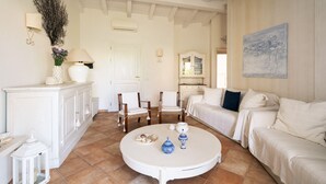 Een ruime woonkamer met een witte bank, een ronde salontafel en een kast.