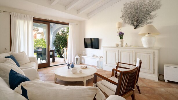 Een woonkamer met een bank, fauteuils, een salontafel, een televisie en een open haard.