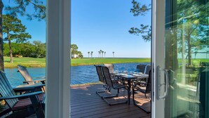 A deck with outdoor seating and a view of a golf course and water. - 🌞Bayfront | Pet Friendly | Golf Cart | Pool | Fairways 274- Sea Ya Later🌞 (Miramar Beach)