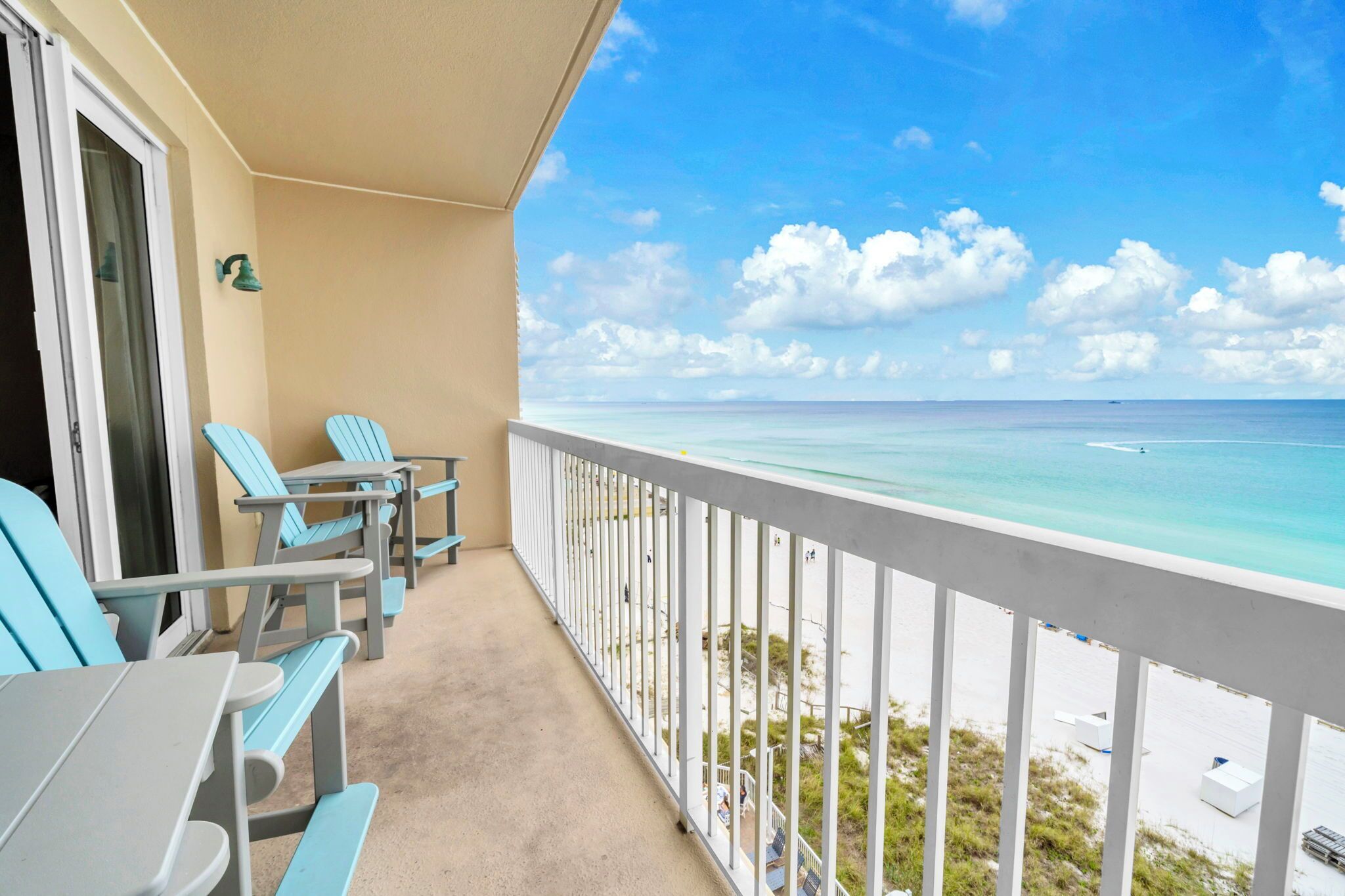 A balcony with a view of the ocean, a table, and two chairs.