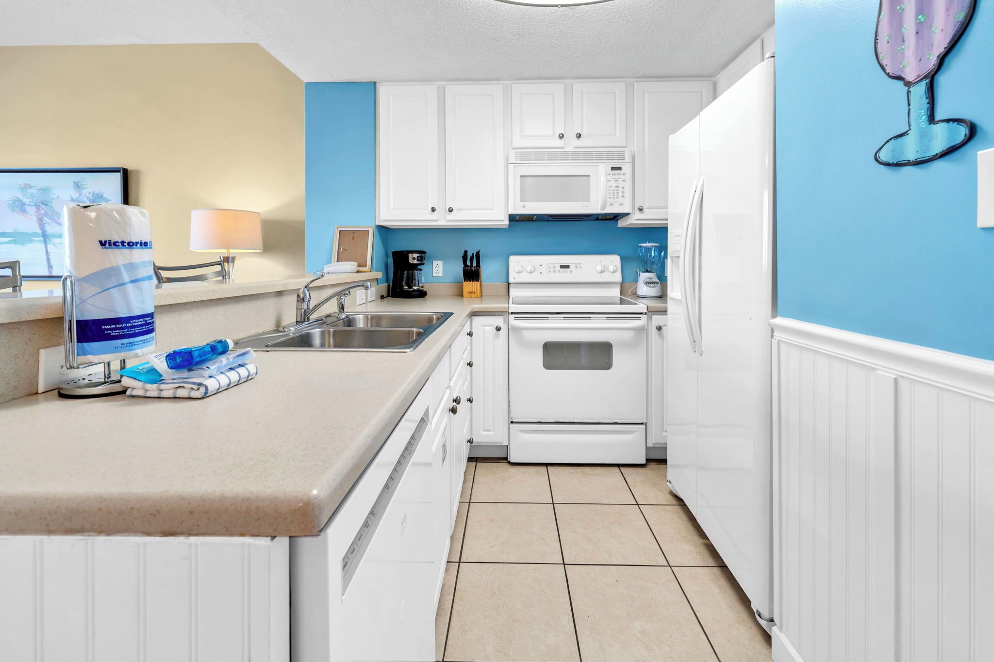 Una cocina con gabinetes blancos, un microondas, una estufa y un refrigerador.