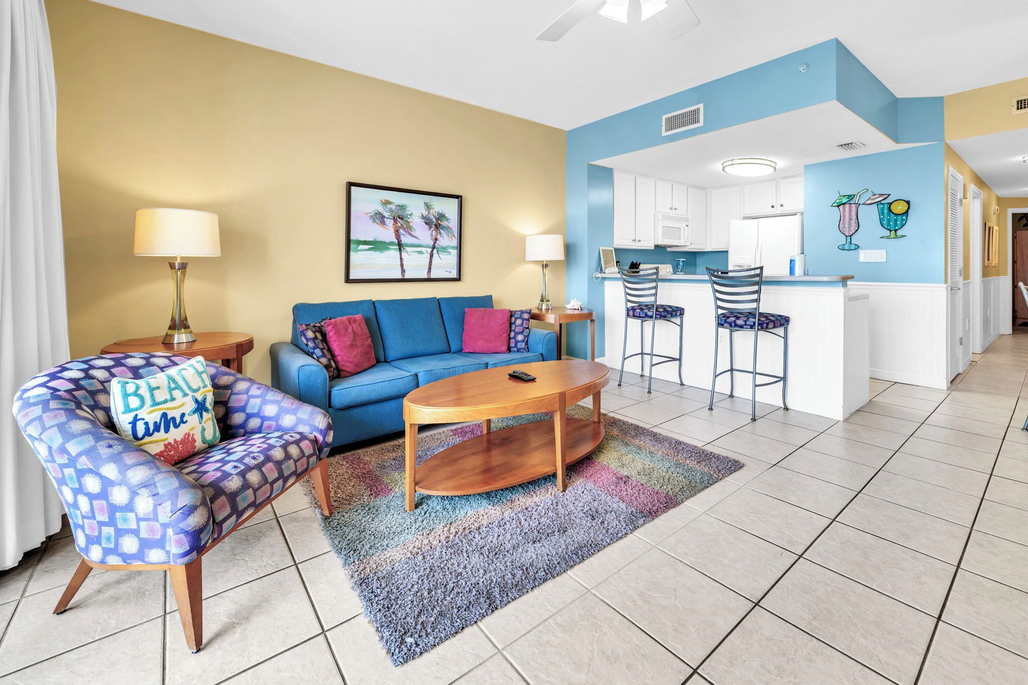 A living room with a sofa, armchair, coffee table, and a painting on the wall.