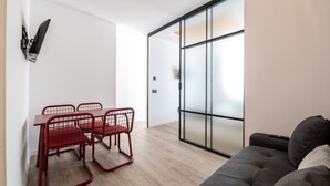 A modern living space with a dining area, a sofa, and a sliding glass door leading to a balcony. - 504 - A33 Signature | Penthouse | Terr | 2BR | 6G (Madrid)