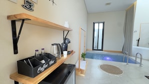 A room with a coffee bar, a small pool, and a window with curtains.