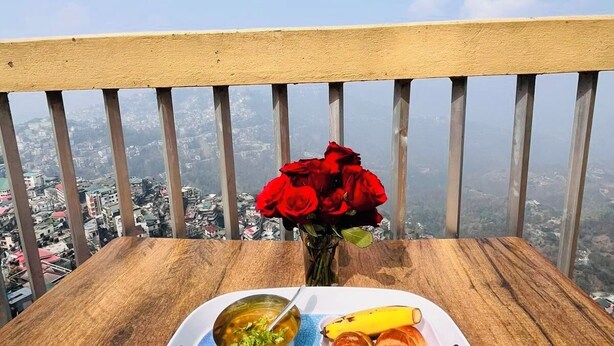 Ein Tablett mit Speisen und einer Tasse auf einem Balkon mit Blick auf die Stadt.