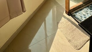 Ein Zimmer mit großen Fenstern, einer Holztür und einem Fliesenboden.