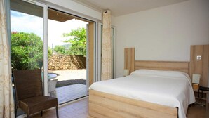 Ein Schlafzimmer mit Bett, Stuhl, einer Schiebetür zu einem Außenbereich und einem Holzkopfende.