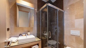 Een moderne badkamer met een douche met glazen wand, een witte wastafel en een spiegel erboven.