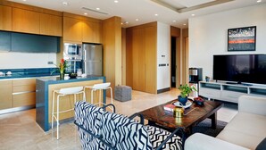 Een moderne keuken met houten kasten, een centraal eiland en een zithoek met een gestreept bankje en barkrukken.