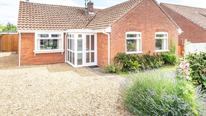 A brick house with a tiled roof, a garage, and a gravel driveway. - Harpers - sleeps 6 guests  in 3 bedrooms (Burnham Market)