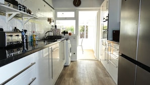 A modern kitchen with white cabinets, stainless steel appliances, and a view to the outside. - Harpers - sleeps 6 guests  in 3 bedrooms (Burnham Market)