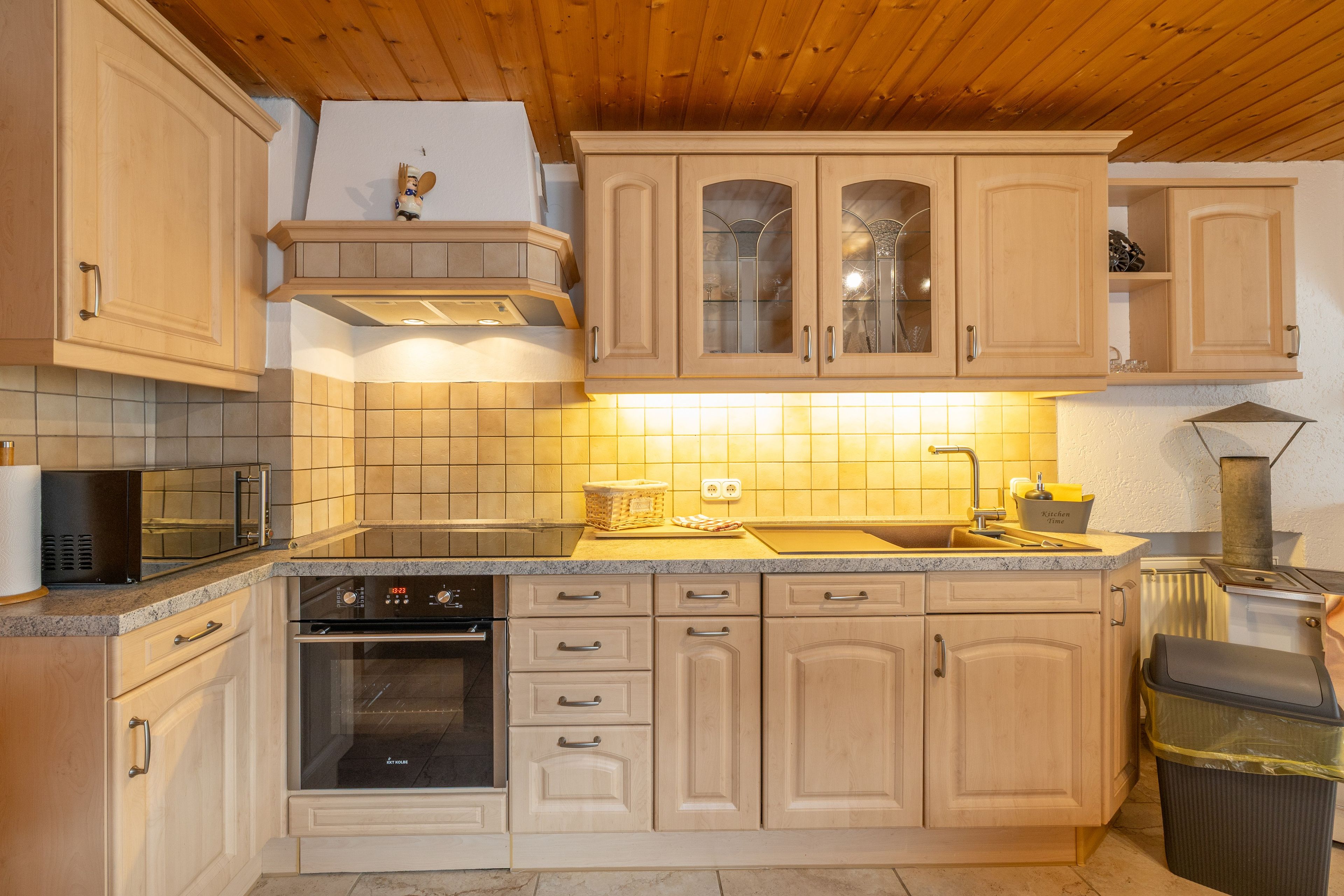 Eine Küche mit Holzausstattung, einer Mikrowelle, einem Backofen und einem Spülbecken.