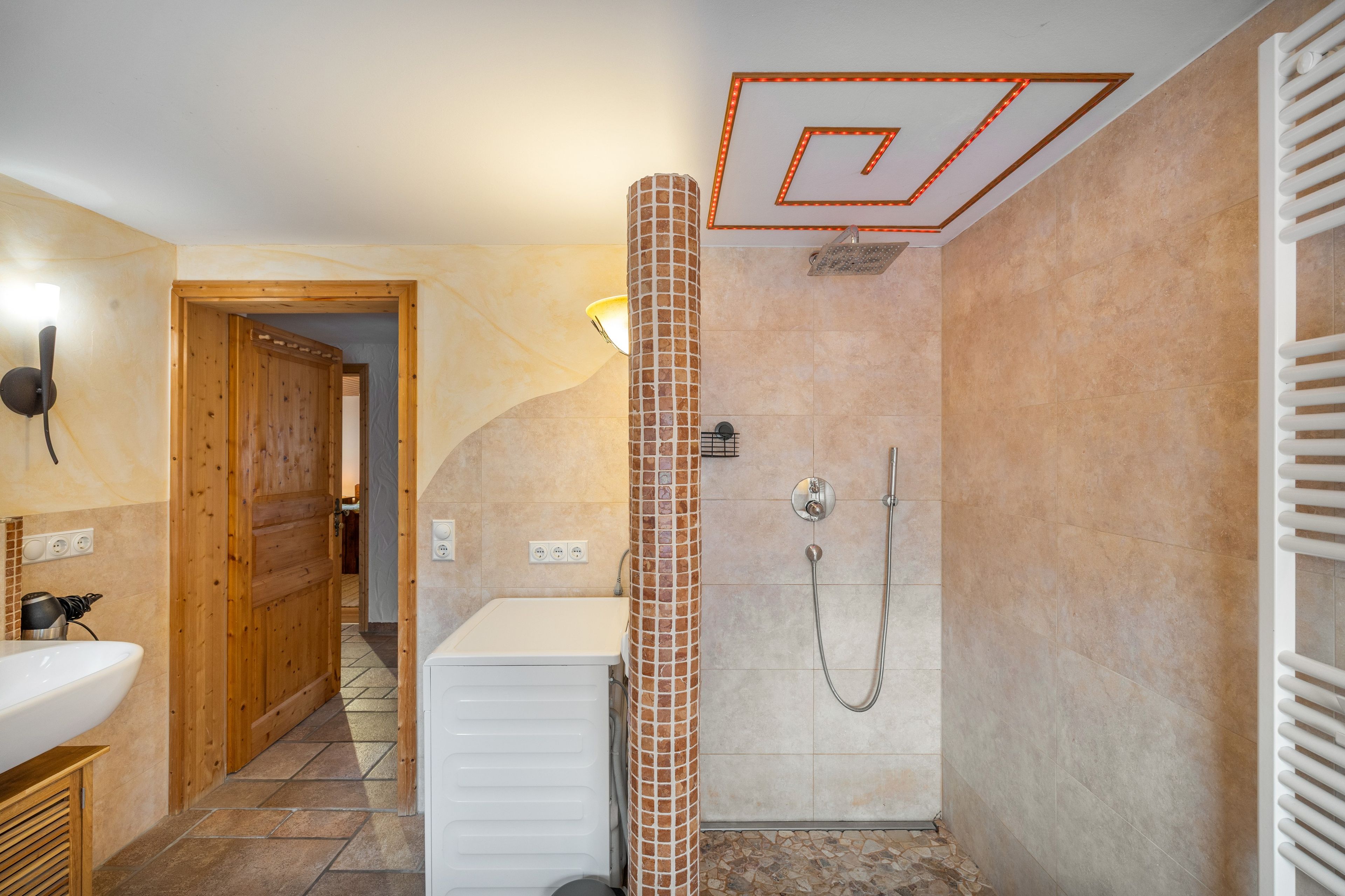 Ein Badezimmer mit Dusche, Waschbecken und einer Holztür.