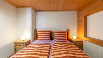 Ein Schlafzimmer mit zwei Betten, einem Holzkopfende, Nachttischlampen und einem Fenster.