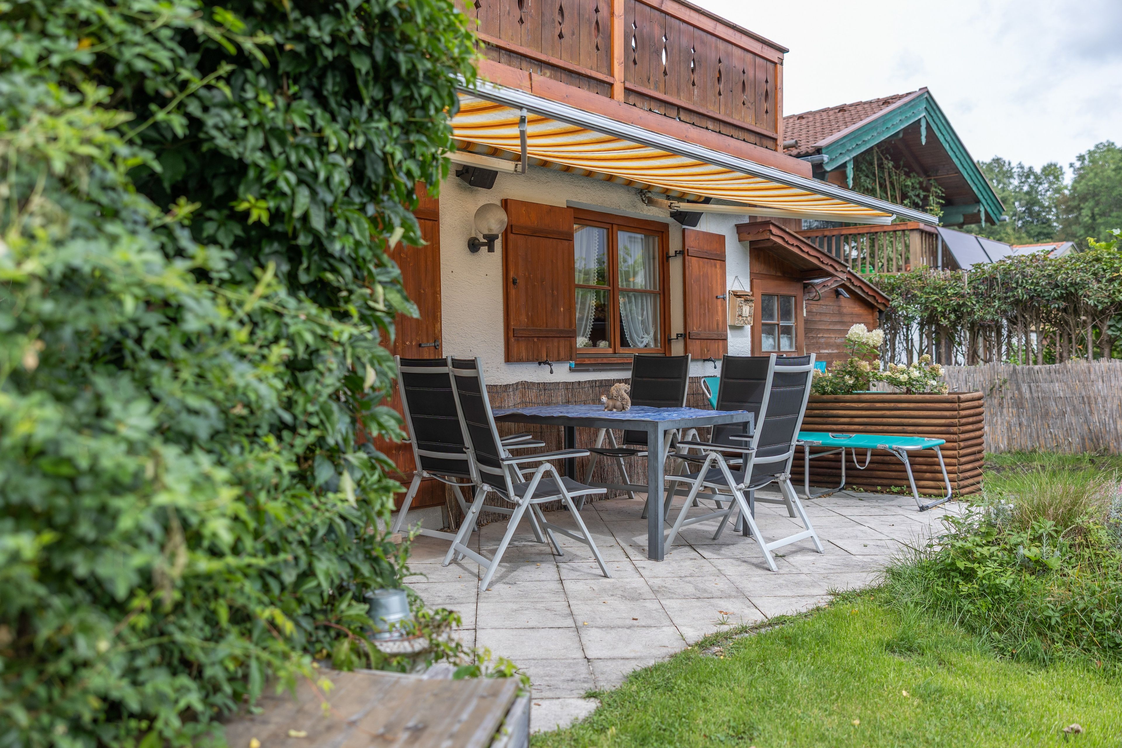 Ein Holzhaus mit Terrasse, Sitzgelegenheiten im Freien und einem Holzzaun.