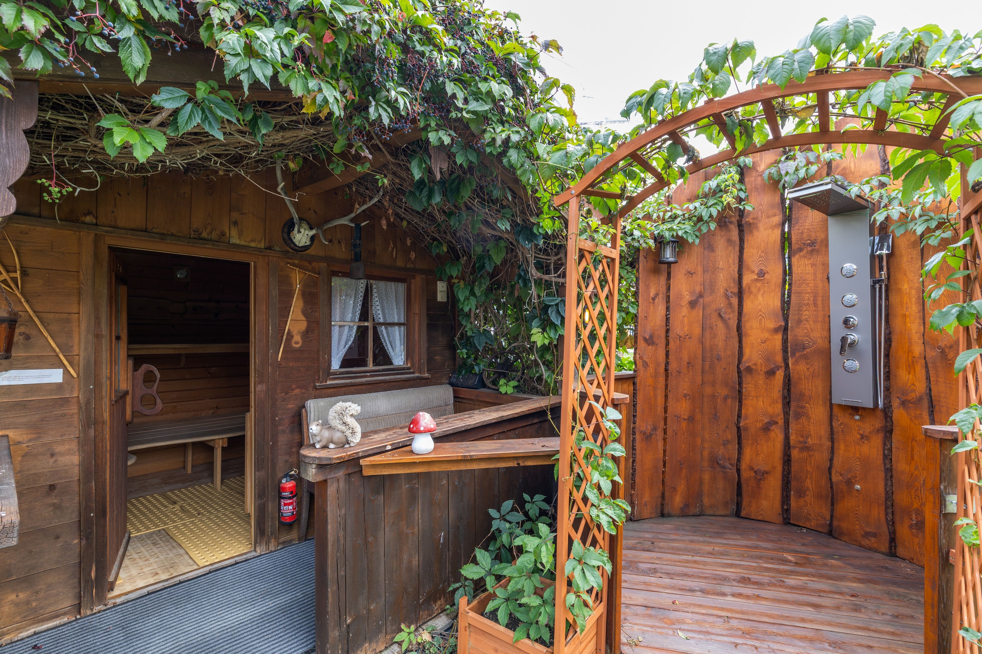 Eine Holzhütte mit einer Holzdielenveranda, einer kleinen Veranda und einer Metalttür.
