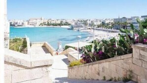 Una vista sulla costa con cielo sereno, una spiaggia e una scala di pietra che conduce all'acqua.