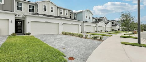 A residential street with houses, driveways, and a sidewalk.