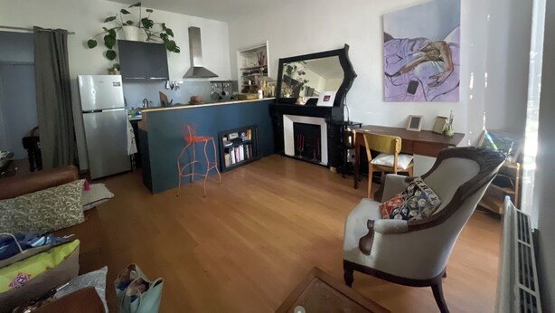 Uma sala de estar com lareira, uma área de jantar e uma cozinha com geladeira e armários.