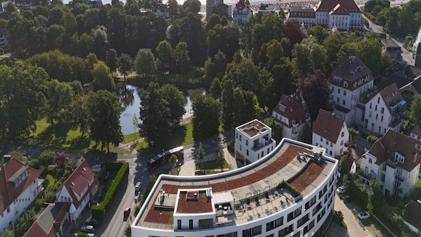 A coastal town with a mix of traditional and modern architecture, a curved building with a flat roof, and a body of water in the background. - 4 Star Holiday Home in Travemunde (Lübeck)