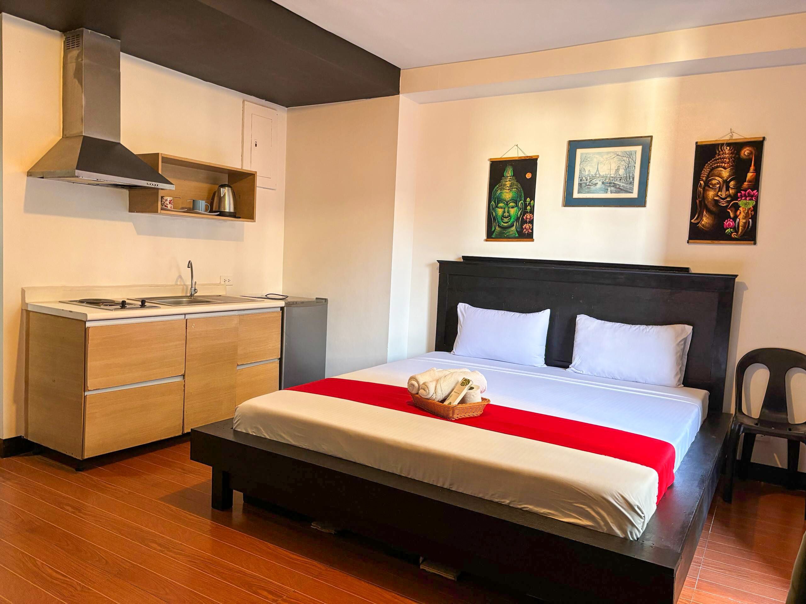 Een slaapkamer met een bed, een kitchenette en kunstwerken aan de wanden.