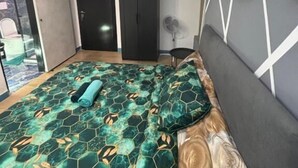 Ein Schlafzimmer mit einem Bett, einem Kleiderschrank, einer Tür und einer Wand mit gerahmten Bildern.