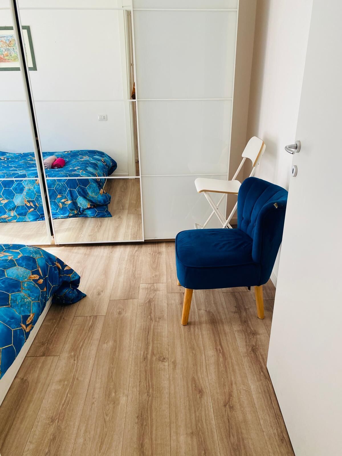 Een kamer met een bed, een stoel en een spiegel.