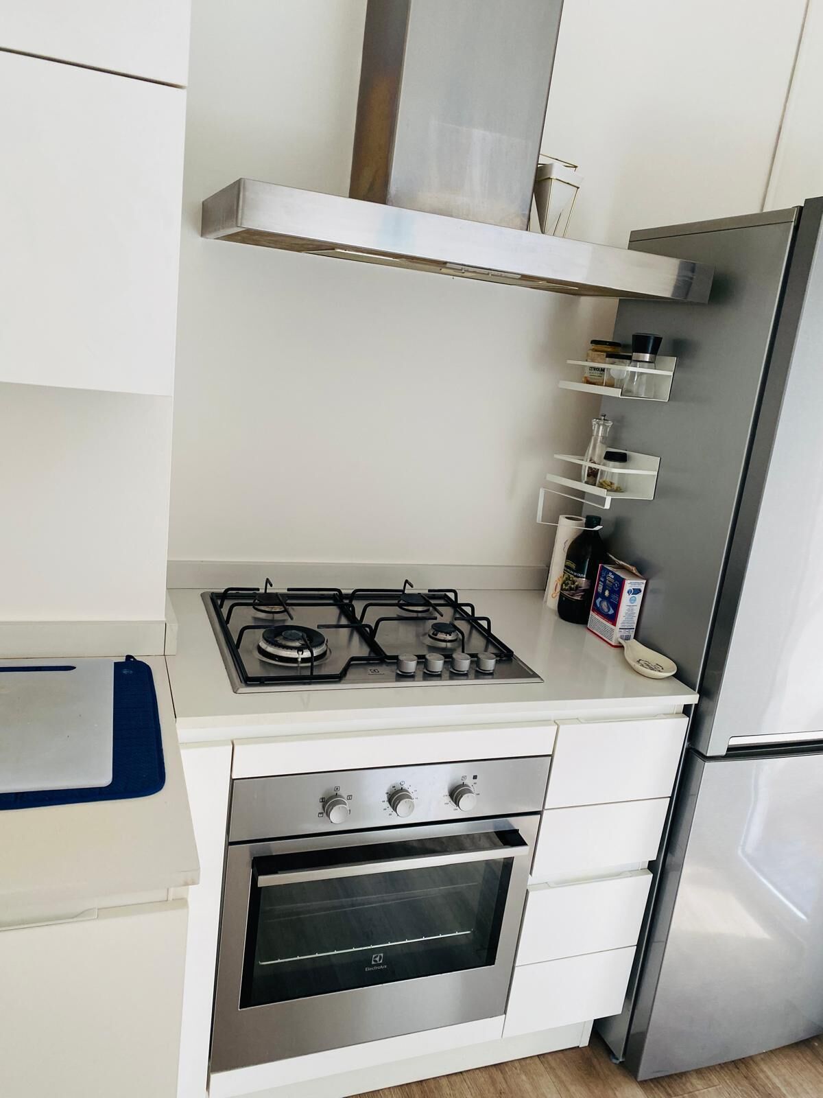 Een keuken met een gasfornuis, oven en een roestvrijstalen koelkast.