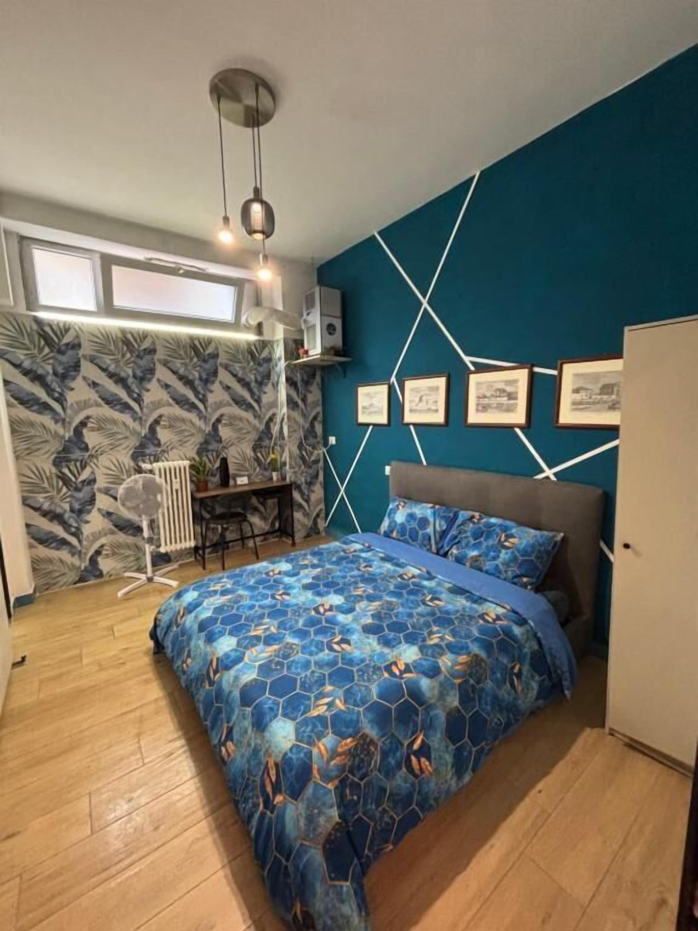 A bedroom with a bed, a desk, and a radiator.