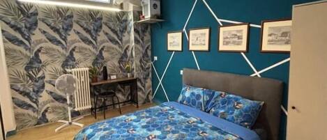 A bedroom with a bed, a desk, and a radiator.