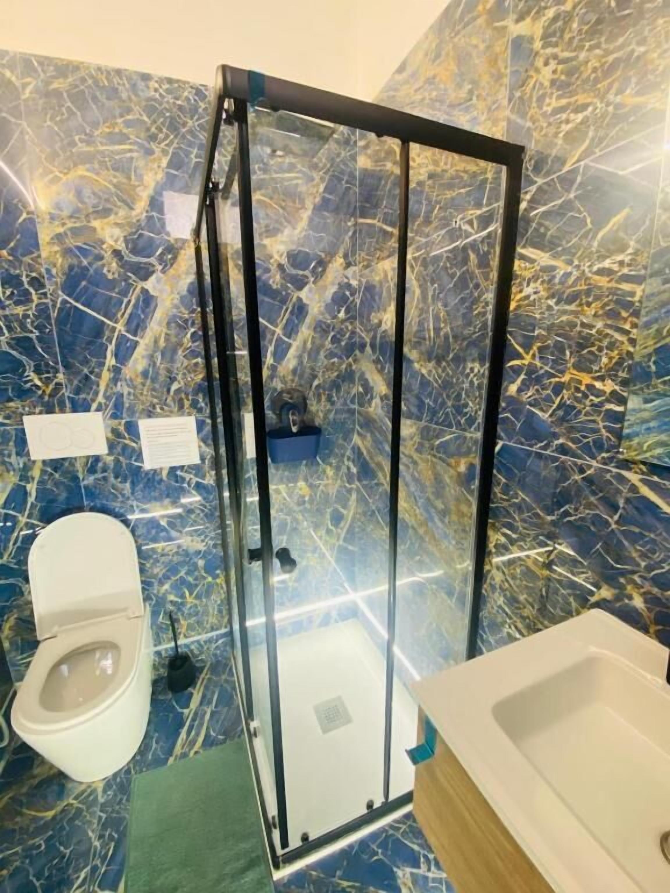 A bathroom with a glass-enclosed shower, a toilet, and a sink.