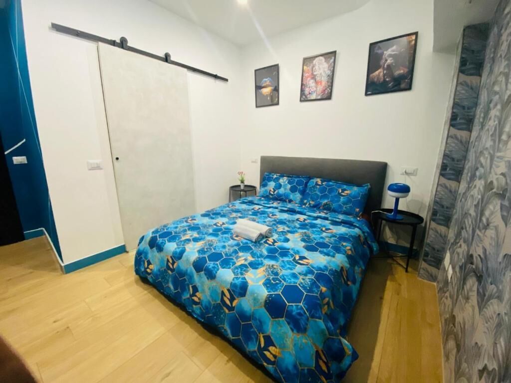 Une chambre à coucher comprenant un lit, une table de chevet, une étagère fixée au mur et une porte.