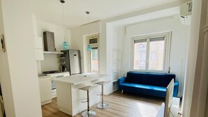 Eine moderne Küche mit Essbereich, einem blauen Sofa und einem großen Fenster.