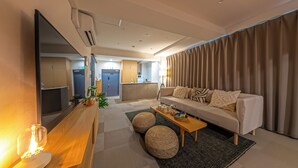 Una sala de estar moderna con un sofá, otomanas, una mesa de centro y un televisor.
