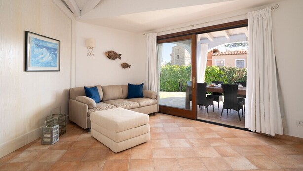 Un salon comprenant un canapé, un pouf et un coin repas avec des chaises et une table.