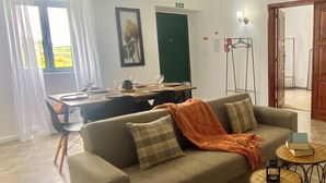 Una sala de estar con un sofá, una mesa de comedor y una araña.
